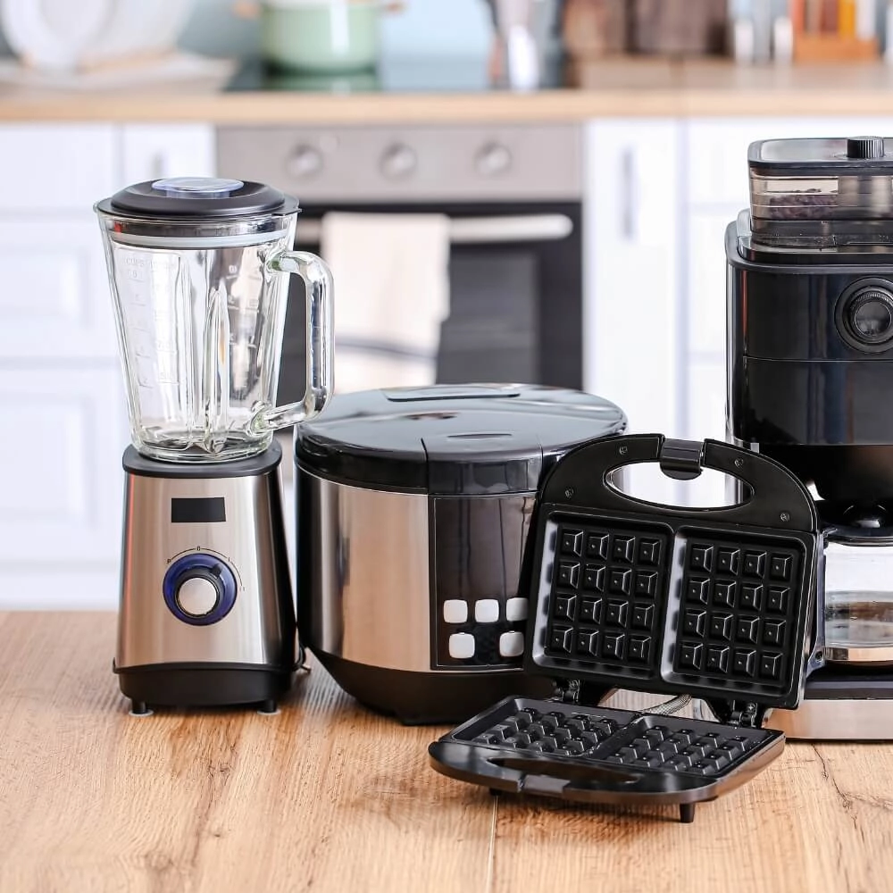 Um liquidificador, air frayer e maquina de fazer café em cima de uma mesa de madeira
